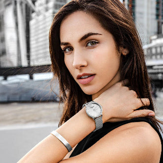 Woman wearing a silver watch with a cityscape background