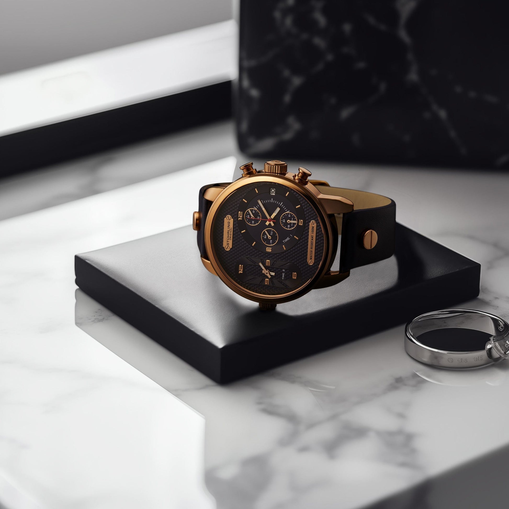 Luxury watch with black leather strap and gold accents on a marble surface